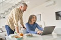 Happy middle aged couple having fun using laptop computer at home. Royalty Free Stock Photo