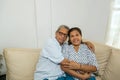 Happy middle-aged couple in love sitting on the couch hugging, husband and wife with gray hair laughing pose facing the camera Royalty Free Stock Photo