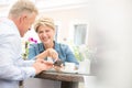 Happy middle-aged couple using mobile phone at sidewalk cafe Royalty Free Stock Photo