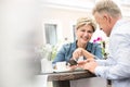 Happy middle-aged couple using mobile phone at sidewalk cafe Royalty Free Stock Photo