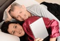 Happy middle-aged couple watching video on tablet at home Royalty Free Stock Photo