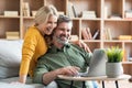 Happy middle aged couple websurfing on laptop together while relaxing at home Royalty Free Stock Photo