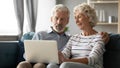 Happy middle aged family couple relaxing on sofa, using computer. Royalty Free Stock Photo