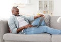 Happy middle-aged freelancer using modern laptop computer, having part-time job at home, sitting on sofa Royalty Free Stock Photo