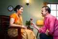 Happy middle aged indian man proposing his wife by giving red rose at home - concept of wedding anniversary, affection Royalty Free Stock Photo