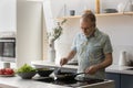 Happy middle aged man cooking food in kitchen. Royalty Free Stock Photo