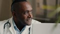 Happy middle-aged man doctor positive medical worker sits at hospital clinic cheerful smiling makes approval hand