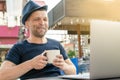 A happy and happy middle-aged man drinks coffee in front of a laptop on the street. laughing and smiling, close-up portrait. commu Royalty Free Stock Photo