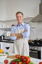 Happy middle aged man wearing apron cooking salad at home, portrait.