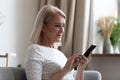 Happy middle aged woman using mobile apps texting at home Royalty Free Stock Photo