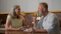 Happy middle-aged old senior couple Caucasian family woman and man drinking orange juice at kitchen home cheerful talk Royalty Free Stock Photo