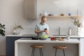 Happy middle aged 60s man using cellphone cooking in kitchen. Royalty Free Stock Photo