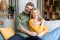 Happy Middle Aged Spouses Relaxing On Couch At Home And Hugging Royalty Free Stock Photo