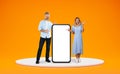 Happy middle aged spouses standing by big phone, blank space Royalty Free Stock Photo