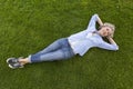 Happy middle-aged woman in casual weekend clothing relaxing on the grass in a park Royalty Free Stock Photo