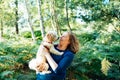 Happy middle-aged woman embracing her cockapoo puppy pet dog during walk outdoors in summer forest or park on sunset. Cute little Royalty Free Stock Photo