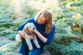 Happy middle-aged woman embracing her cockapoo puppy pet dog during walk outdoors in summer forest or park on sunset Royalty Free Stock Photo