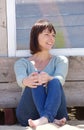 Happy middle aged woman in jeans sitting outside