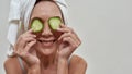 Happy middle aged woman making cucumber mask on eyes