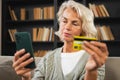 Happy middle aged woman shopping online with smartphone paying with credit card. Mature lady buying on Internet enter Royalty Free Stock Photo