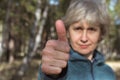 Happy middle-aged woman showing thumbs up, standing on the street in the park, focus on hand. Recommendations concept Royalty Free Stock Photo