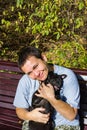 Happy middle-aged woman smiling enjoying her black pug dog on bench on parknatural background Royalty Free Stock Photo