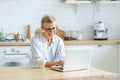 Happy middle aged woman typing something on keyboard while working or studying on laptop at home Royalty Free Stock Photo