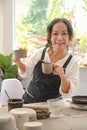 Happy middle aged woman wearing apron handicraft crockery and smiling to camera. Activity, handicraft, hobbies concept