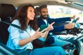 Happy middle eastern couple driving using cellphone gps app, woman passenger showing way to driver man