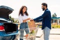 Happy middle eastern couple packing grocery bags into a car trunk, arab man giving paper bag to wife Royalty Free Stock Photo