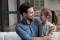 Happy millennial affectionate daddy hugging daughter girl with love