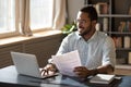 Happy millennial african american businessman in eyewear doing paperwork.