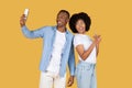 Happy African American man taking a selfie with his smartphone as the woman next to him points upwards Royalty Free Stock Photo