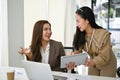 A happy Asian female worker showing something on her tablet screen to her boss Royalty Free Stock Photo