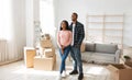 Happy millennial black couple standing in their new house among cardboard boxes on moving day Royalty Free Stock Photo