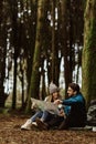 Happy millennial caucasian couple in jackets with backpack rest, take break in cold forest, watch map Royalty Free Stock Photo