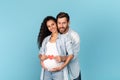 Happy millennial caucasian man with beard hugging pregnant arabic woman, holding heart on belly Royalty Free Stock Photo