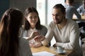 Happy millennial couple getting keys to new house from realtor