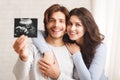 Happy millennial couple holding ultrasound scan of their expecting baby Royalty Free Stock Photo
