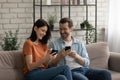 Happy millennial couple relax on sofa using cellphones Royalty Free Stock Photo