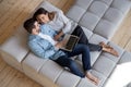 Happy millennial couple relax on sofa using laptop at home Royalty Free Stock Photo