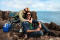 Happy Millennial Couple Relaxing In Camping Chairs On Beachrocks Near Ocean