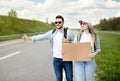 Happy millennial couple standing along highway with empty sign, stopping car, having road trip, mockup for design
