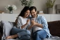 Happy millennial couple using online app on mobile phone together