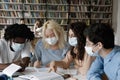 Happy millennial diverse students in facial masks preparing for exams.
