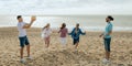 Happy millennial european and arab men play at ball game or volleyball, enjoy weekend on beach Royalty Free Stock Photo