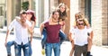 Happy millennial friends couples walking in city center on piggyback move - Happy guys and girls having fun around old town Royalty Free Stock Photo