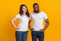 Happy millennial girl and afro guy posing together over yellow background