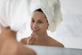 Happy millennial girl applying make up at mirror after shower Royalty Free Stock Photo