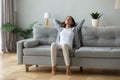 Happy young woman rest on cozy sofa breathing fresh air